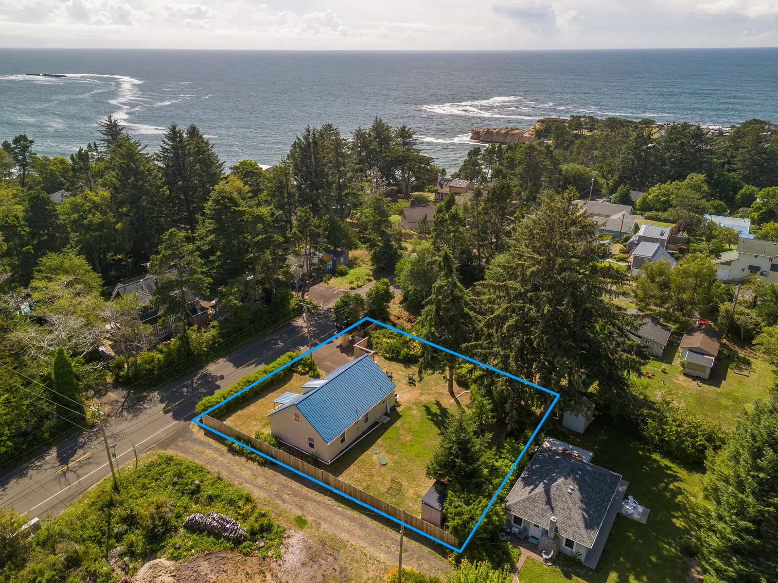 Aerial view of Otter Rock House and its yard, with the shoreline just beyond